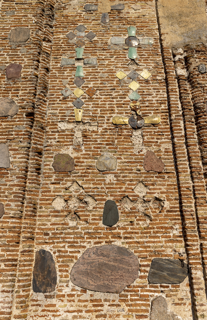 Стены из красного кирпича, украшены полированными камнями и декоративной плиткой