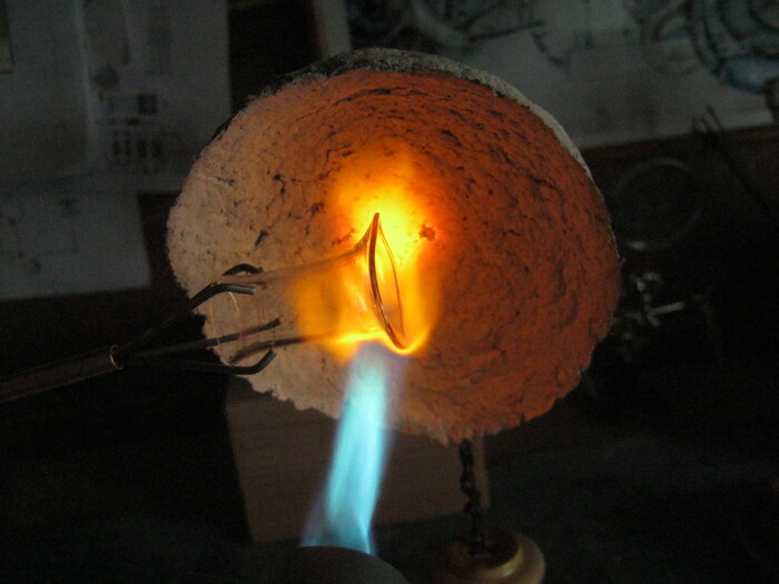 Фото 12. Равномерно разогрев край заготовки, гладким и смазанным воском, ребром медной развертки, вращая заготовку, расширяем горловину трубки. Вынув из пламени.