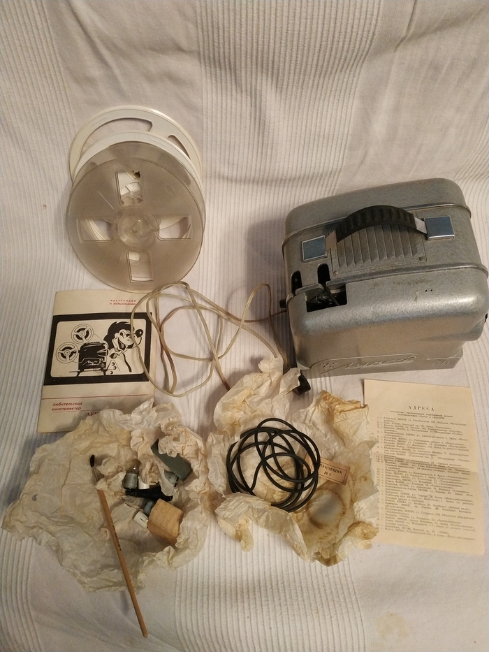 Общий вид комплектации. Пустые бобинки для пленки, пассики, лампочки, предохранители, даже кисточку положили - обмахивать линзы от пыли. Инструкция и список мастерских по ремонту.
