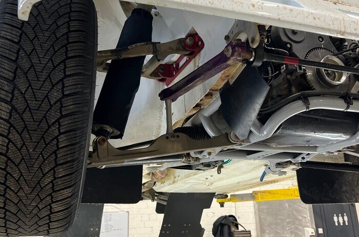 Передняя подвеска двухрычажная, как на серийных Жигулях, но совсем на них не похожа. Выточенный из алюминия нижний поперечный рычаг дополнен диагональной тягой из стальной трубы, верхний A-образный рычаг — целиком алюминиевый.