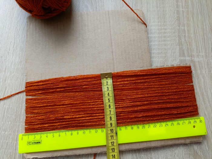 Используя картонный шаблон, намотала акриловую пряжу. Мне нужны были не очень длинные волосы, поэтому разрезала длиной по 30 см и разделила на две части шириной по 9 см.