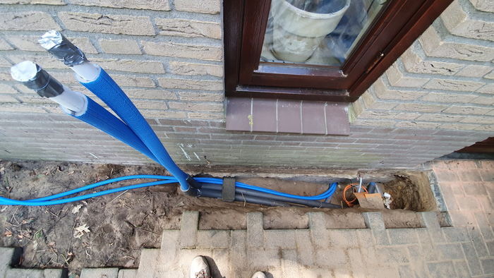 Укладка труб и кабелей для подключения теплонасоса. Трубы композитные, теплоизолированные. Оранжевы провод — это оптоволокно интернета.