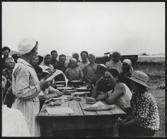 Парторг колхоза "Красный узел" во время обеденного перерыва читает положение о выборах, 1937