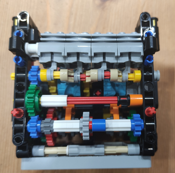 На фото видно три пары шестерён внизу. Они отвечают за три передачи в коробке. Две оранжевые детали внутри переключают передачи.